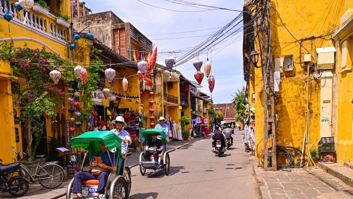 rickshaws and motor scooters on the street in pho co hoi an